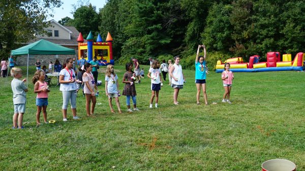 Children lined up outdoors for a game during a sunny day event.