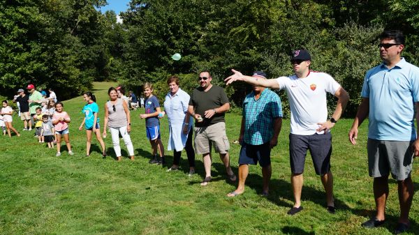 People lined up outdoors playing a game of tossing a ball.