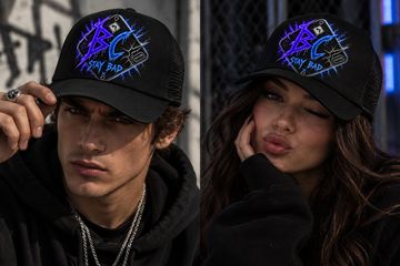 Two young people wearing black caps with neon designs.