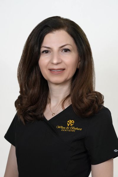 Professional woman in dental uniform with clinic logo.