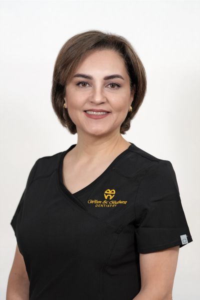 Professional female dentist wearing a black uniform with a dental clinic logo.