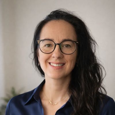 Femme souriante portant des lunettes et une chemise bleu foncé.