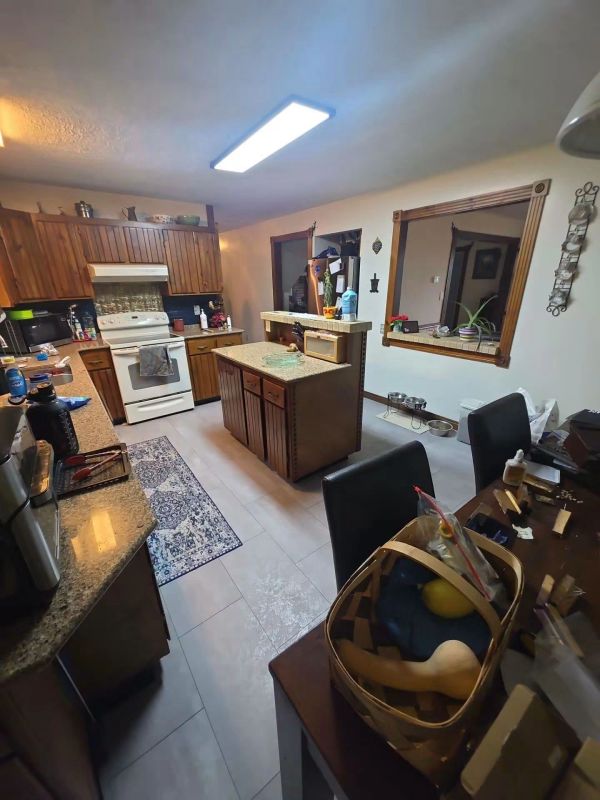 Cozy kitchen with wooden cabinets and island, bright lighting.