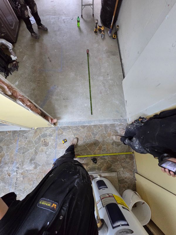 Two workers measuring floor tiles and concrete.
