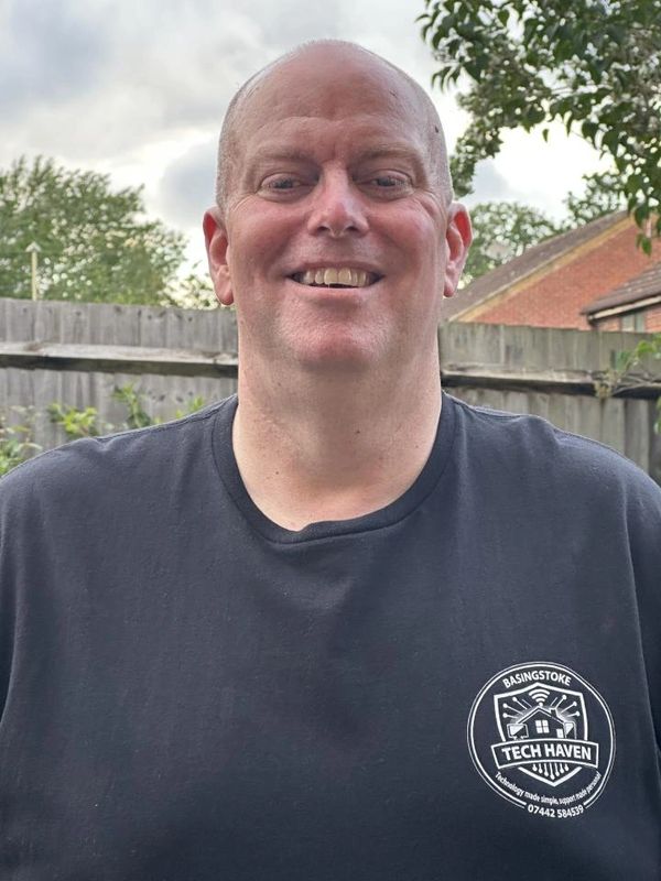 Smiling man wearing a black Tech Haven t-shirt outdoors.