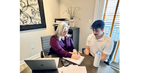 Two people collaborating over documents at a round office table.