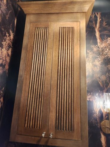 Wooden cabinet with vertical grooves and two small knobs.