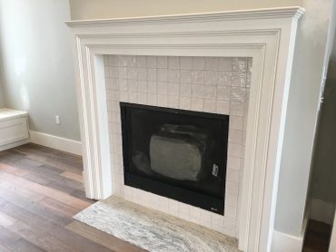 Modern fireplace with white tile surround and marble hearth.