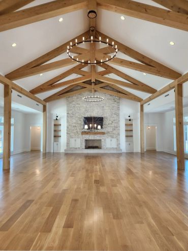 Spacious room with wooden beams and stone fireplace.