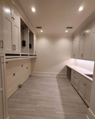 Empty laundry room with white cabinets and gray flooring.