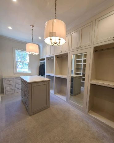Spacious walk-in closet with island and hanging lights.