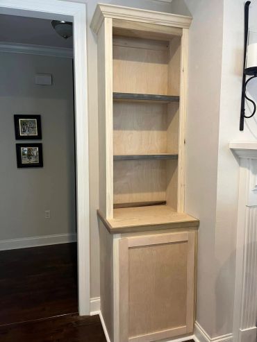 Unfinished wooden built-in bookshelf in a living room.