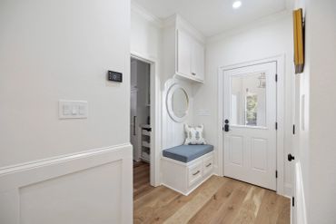 Entryway with a bench and storage under a round mirror.