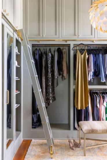 Elegant walk-in closet with hanging clothes and a ladder.