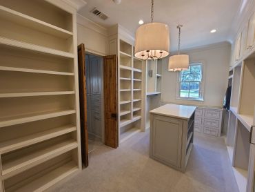 Empty walk-in closet with shelves and island.