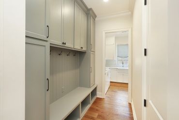 Modern mudroom with gray cabinets and wooden floor.