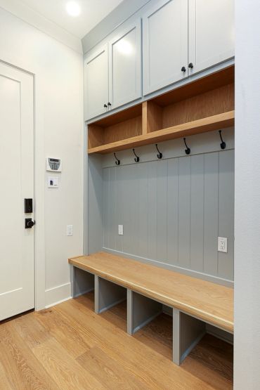 Modern mudroom with bench, hooks, and storage cabinets.