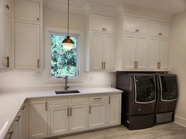 Modern laundry room with white cabinetry and black washer and dryer.
