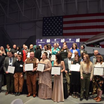Group receiving awards with American flag background.