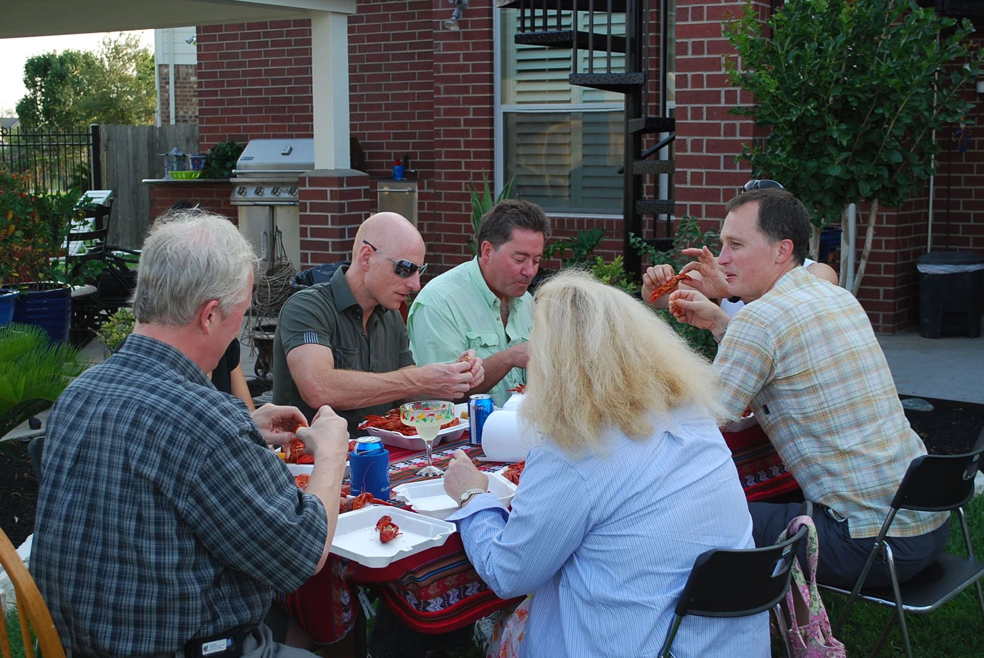 Group of adults enjoying a crawfish meal outdoors.