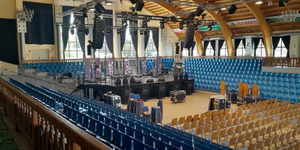 Indoor arena with blue and yellow seats and a central stage setup.