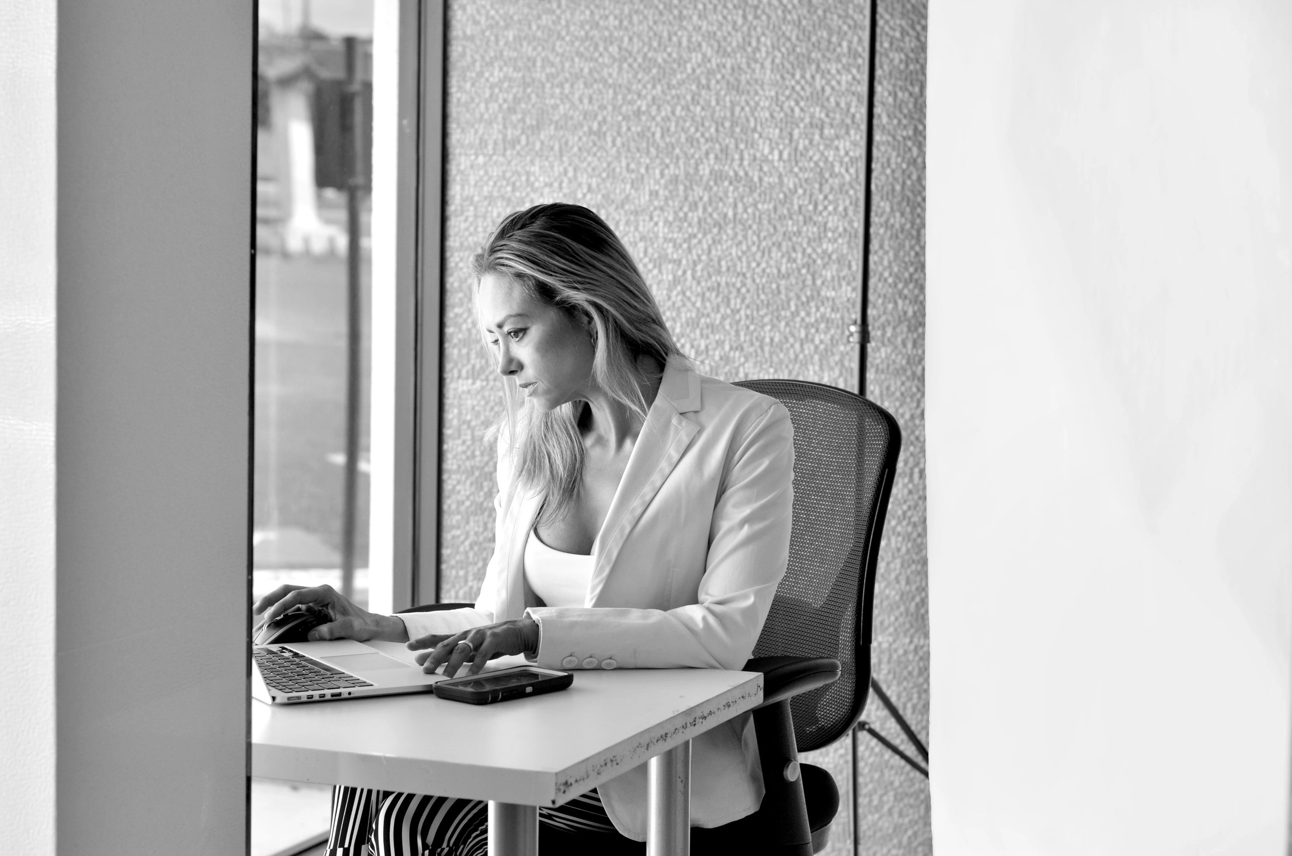 Woman working intently on laptop in a modern office space.