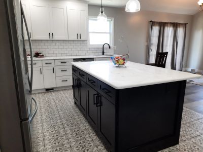 Modern kitchen with black island and patterned floor tiles.