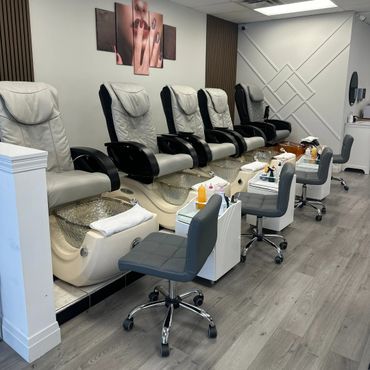 Row of pedicure chairs with foot baths in a clean nail salon.