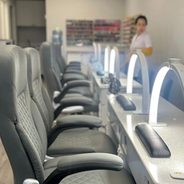 Empty nail salon chairs with manicure lamps and cushions.