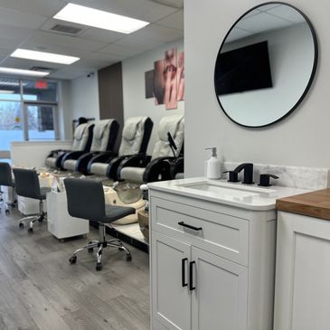 Modern nail salon with pedicure chairs and a clean white sink area.