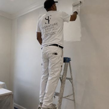 Painter applying white paint on wall.