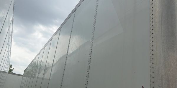 Close-up view of large white trailer walls under a cloudy sky.