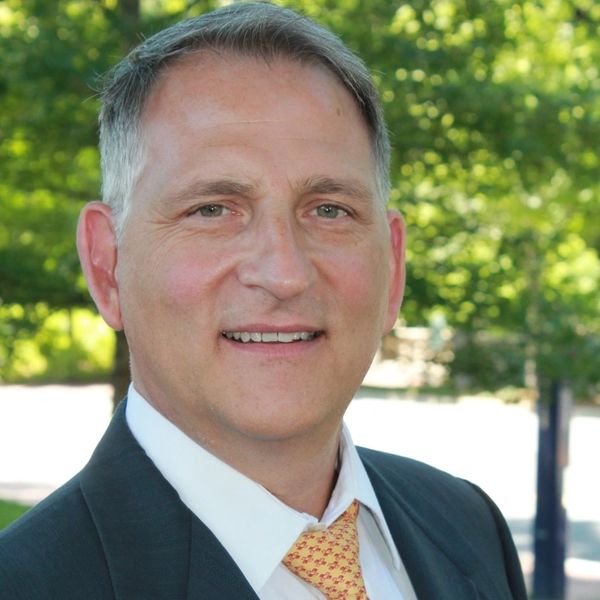 Smiling man in a suit outdoors.
