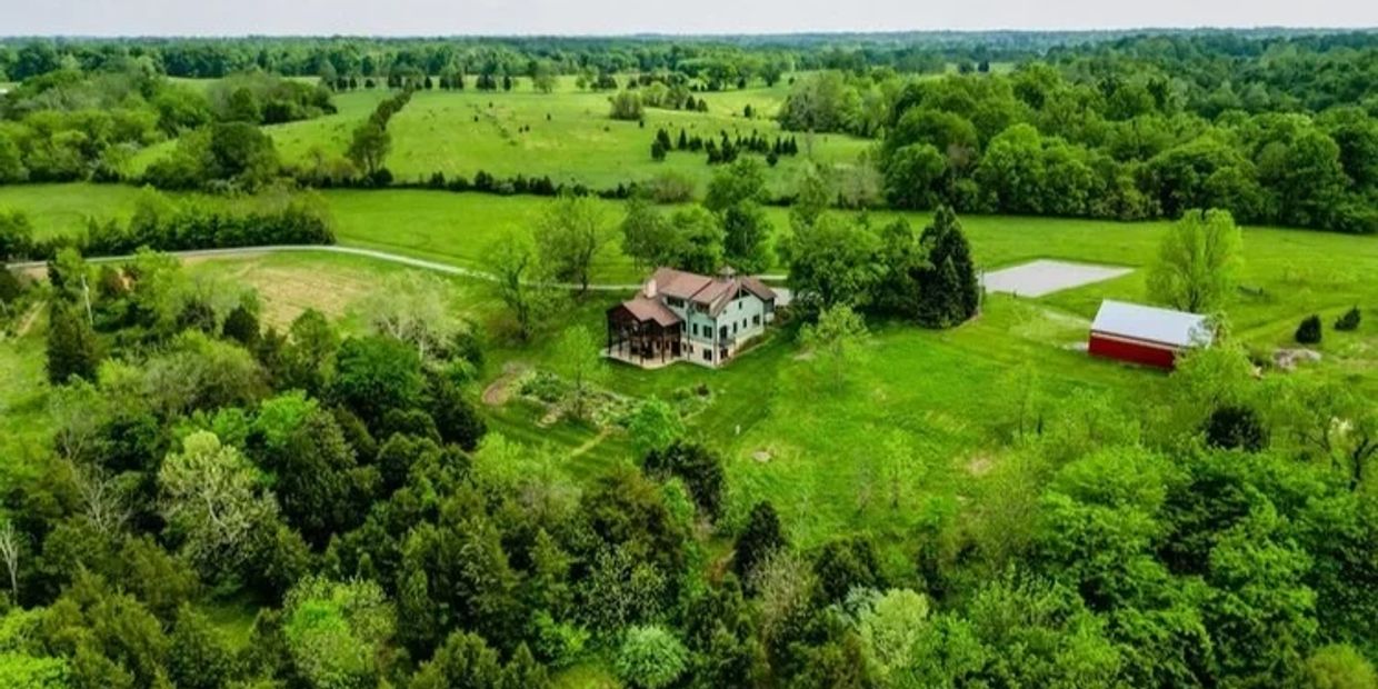 A house and barn on a lush green farmland.
