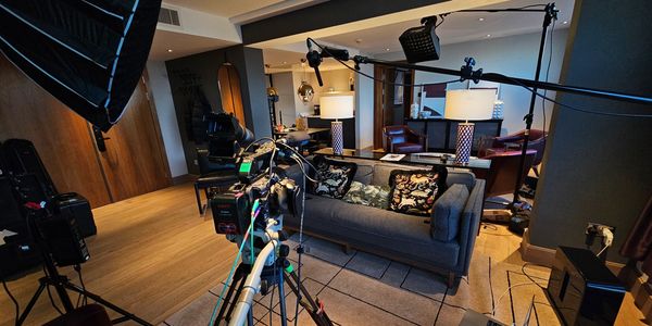 Living room set with camera and lighting equipment.