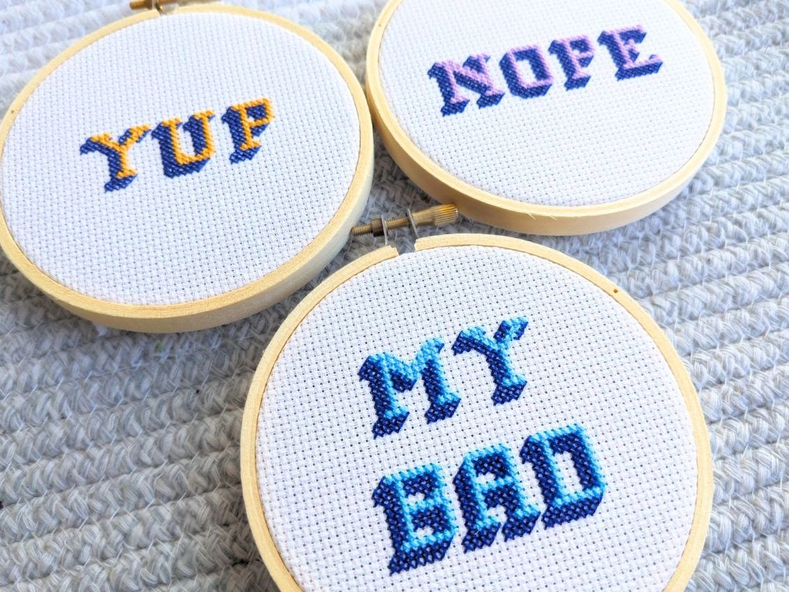 Three small cross stitch hoops with the phrases yup, nope, and my bad in 3d font