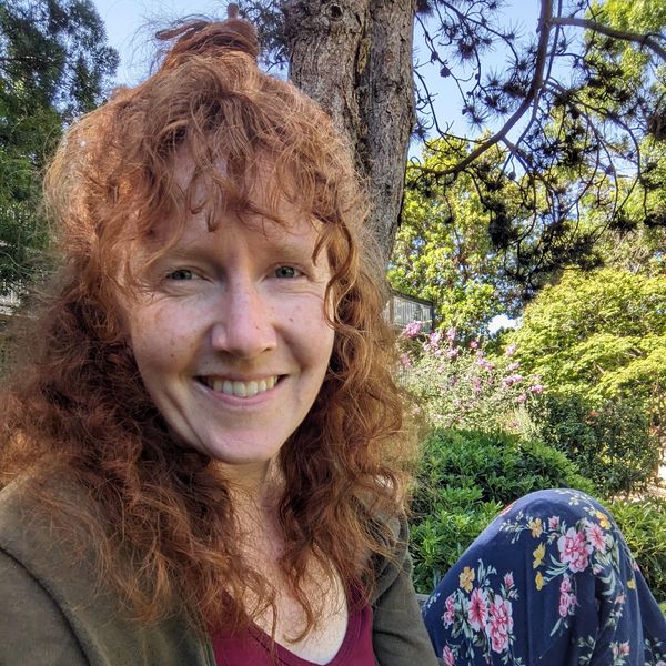 CubicleCrossStitches owner Hannah Baker smiling at the camera in an outdoor setting