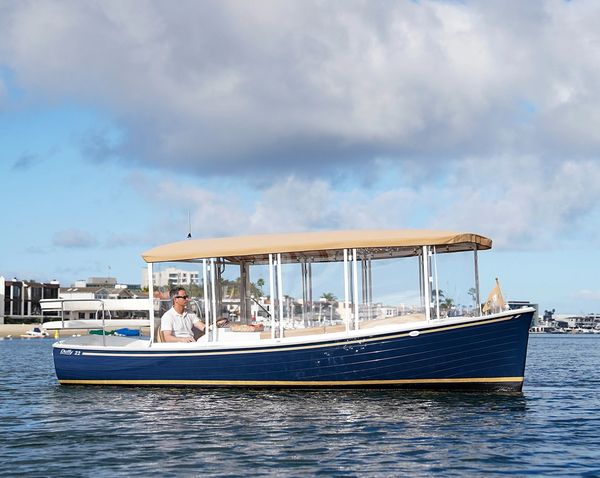 Blue and tan boat on calm water with a man steering.