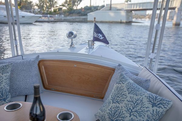 Cozy boat seating area with cushions and wine bottle on table.