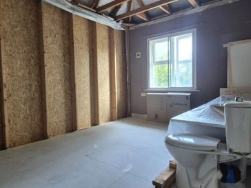 Partially renovated bathroom with exposed wall framing and new fixtures.