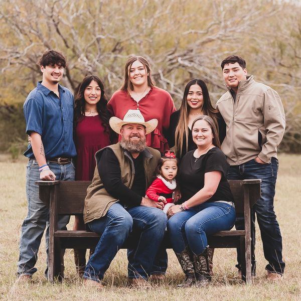 Family portrait outdoors with eight people smiling.