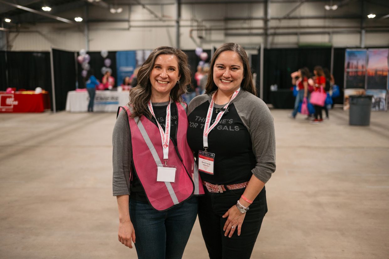 Two women smiling at an indoor event.