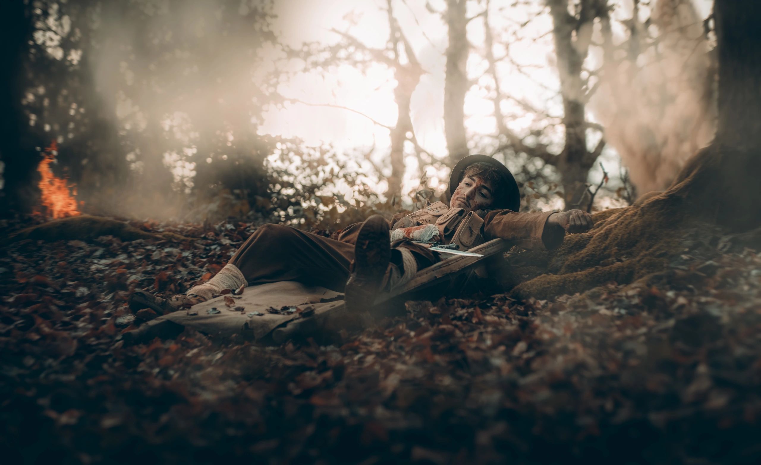 Soldier wounded and resting on stretcher in a forest.