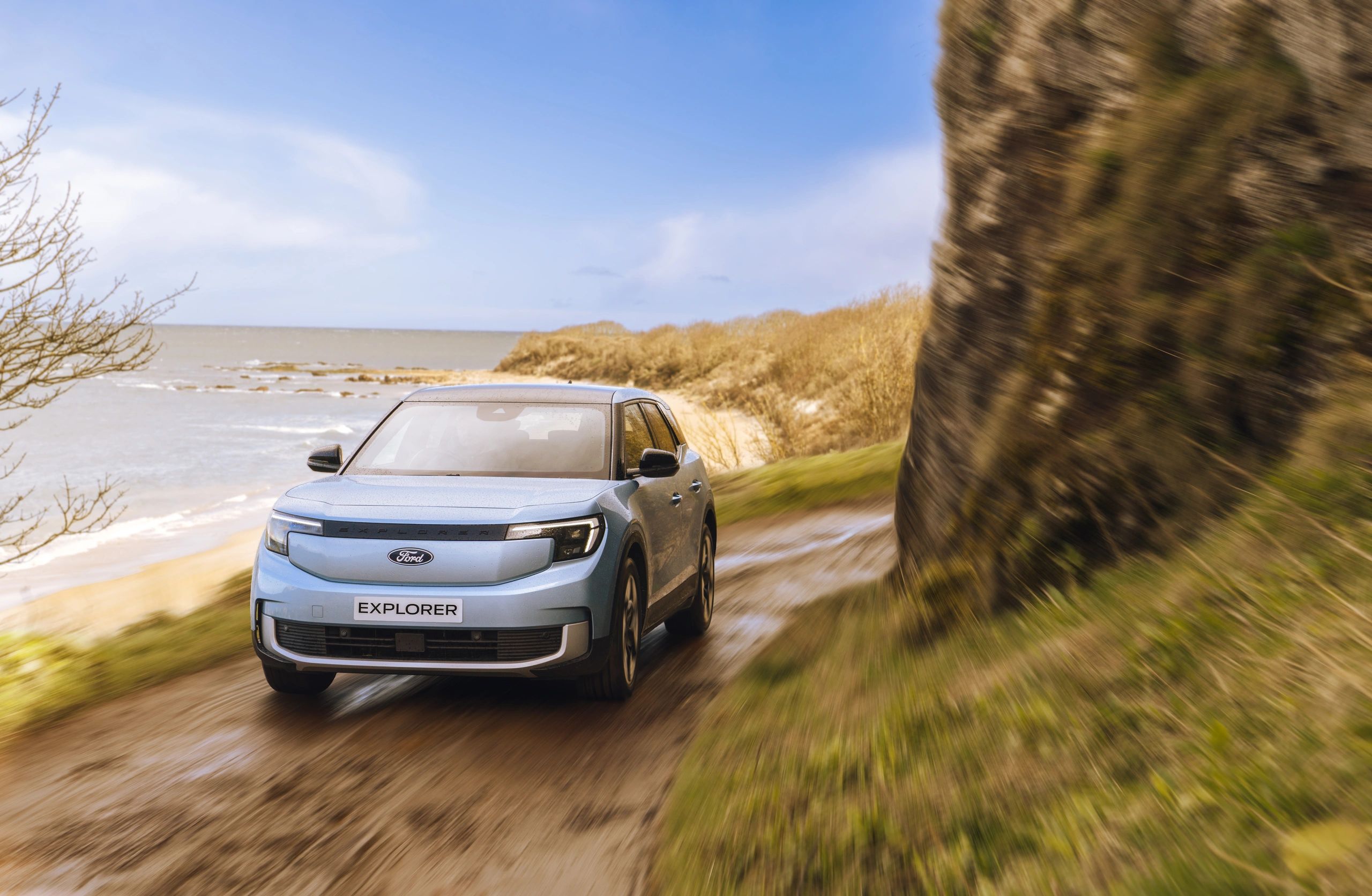 Ford Explorer driving on a coastal dirt road.