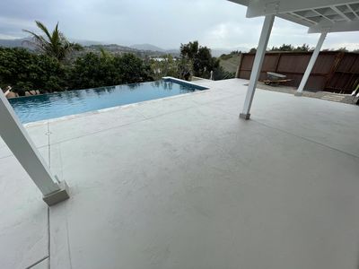 Textured overlay on pool deck with pool in background. Cloudy skies and some trees in the distance.