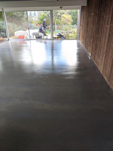 Newly polished concrete floor inside a room with wood-paneled walls and garden view.