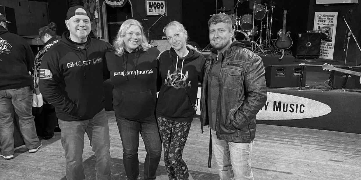 Four people posing happily inside Bobby Mackey's honky-tonk music venue with instruments in the background.