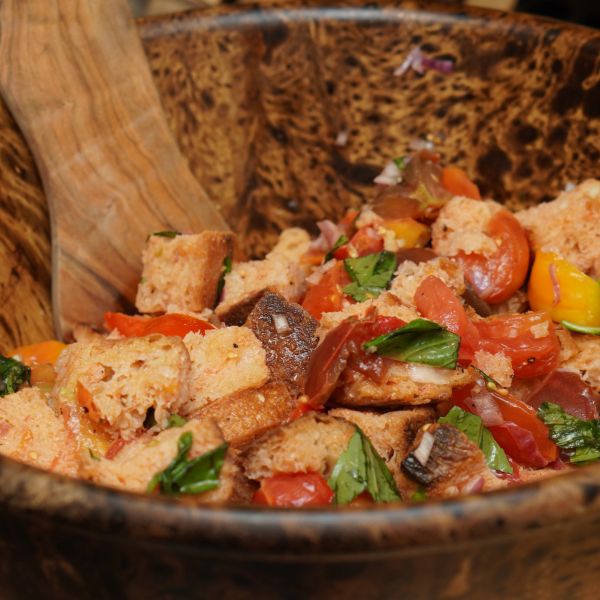 Rustic bowl of fresh panzanella salad with tomatoes, basil, and bread chunks.