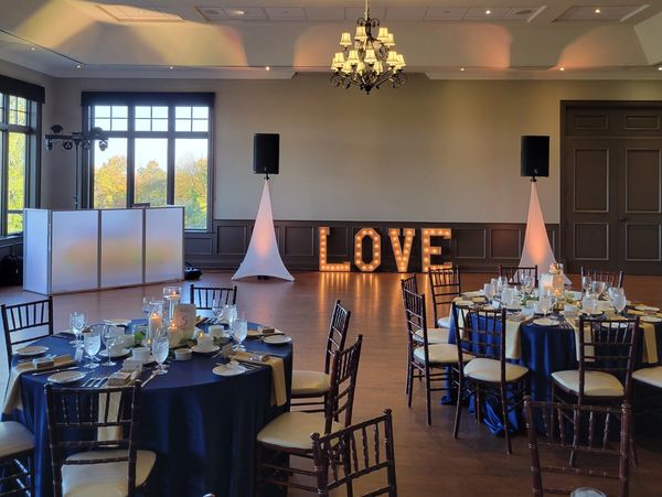 A beautifully decorated event space with LOVE lights and elegantly set tables.