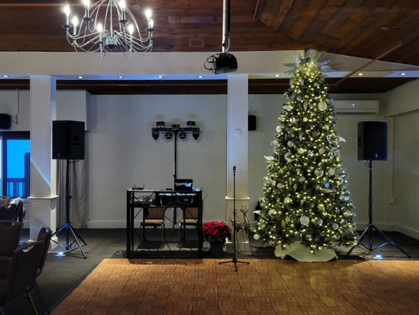 Decorated Christmas tree with DJ setup in a cozy room.